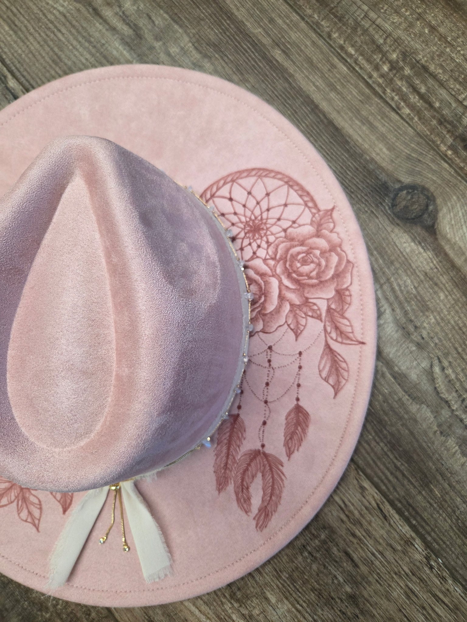 Pink hat with floral design on a wooden surface