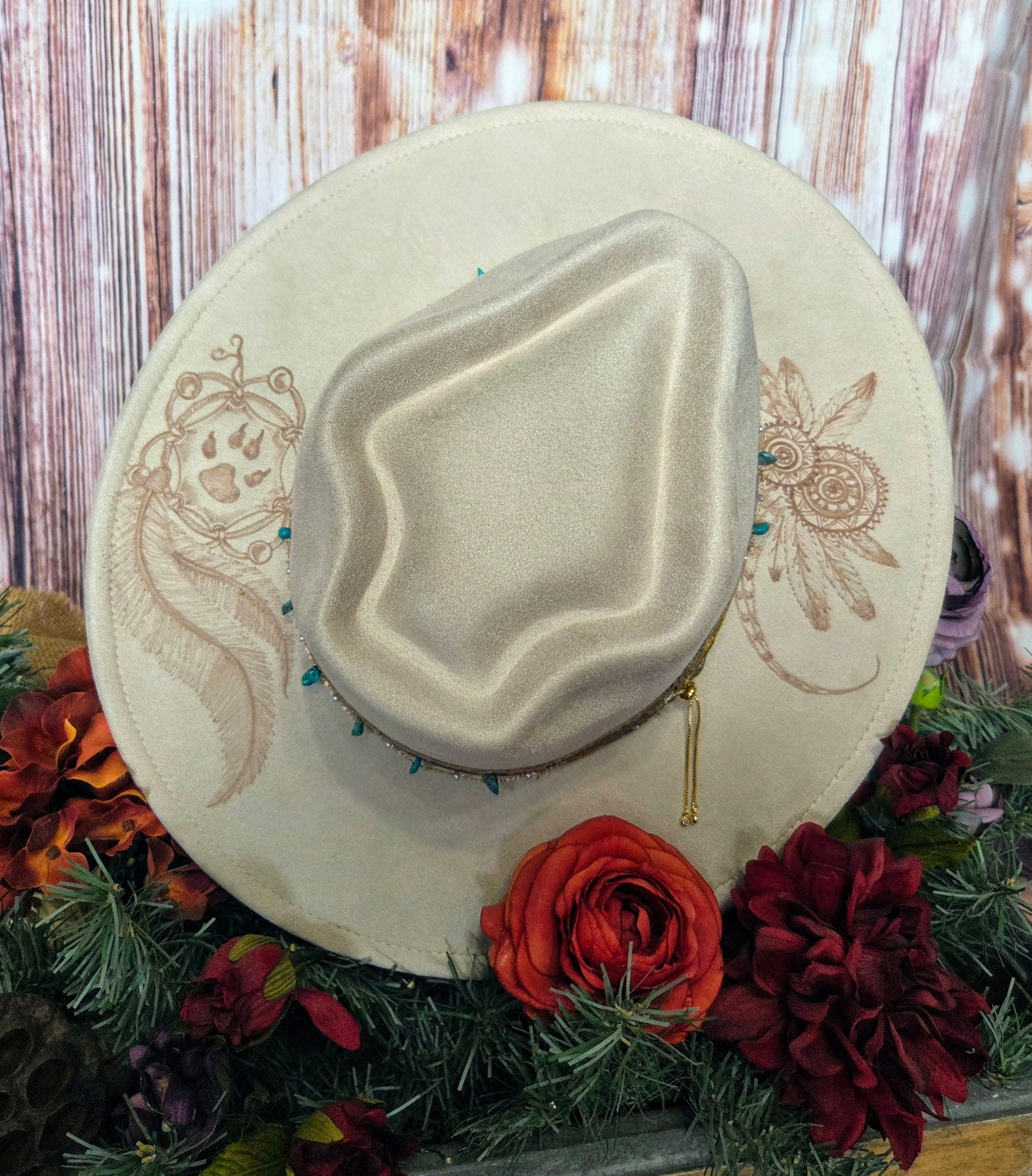 Embroidered beige hat with floral decorations on a wooden background
