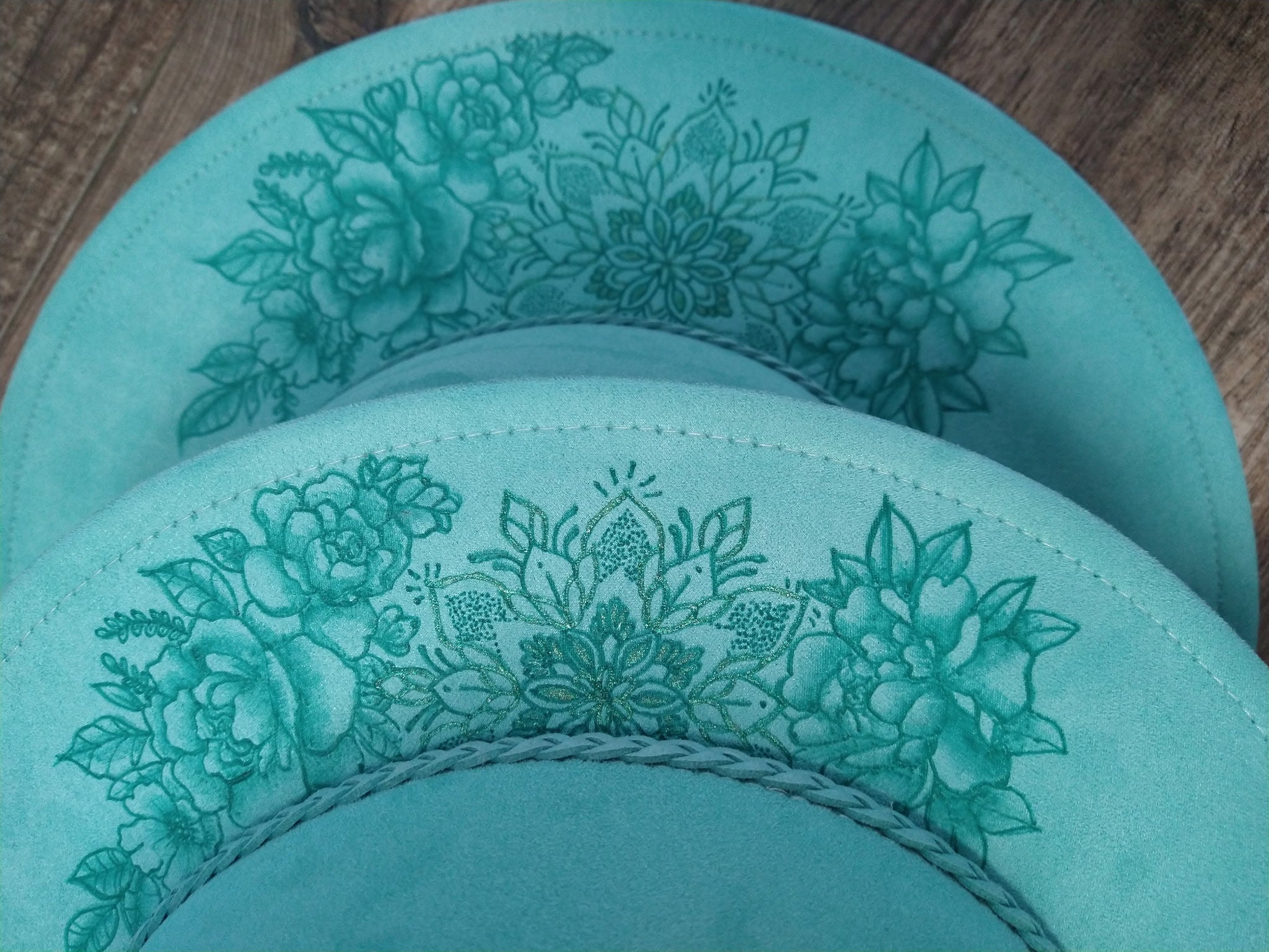 Two hats with floral patterns on a wooden surface