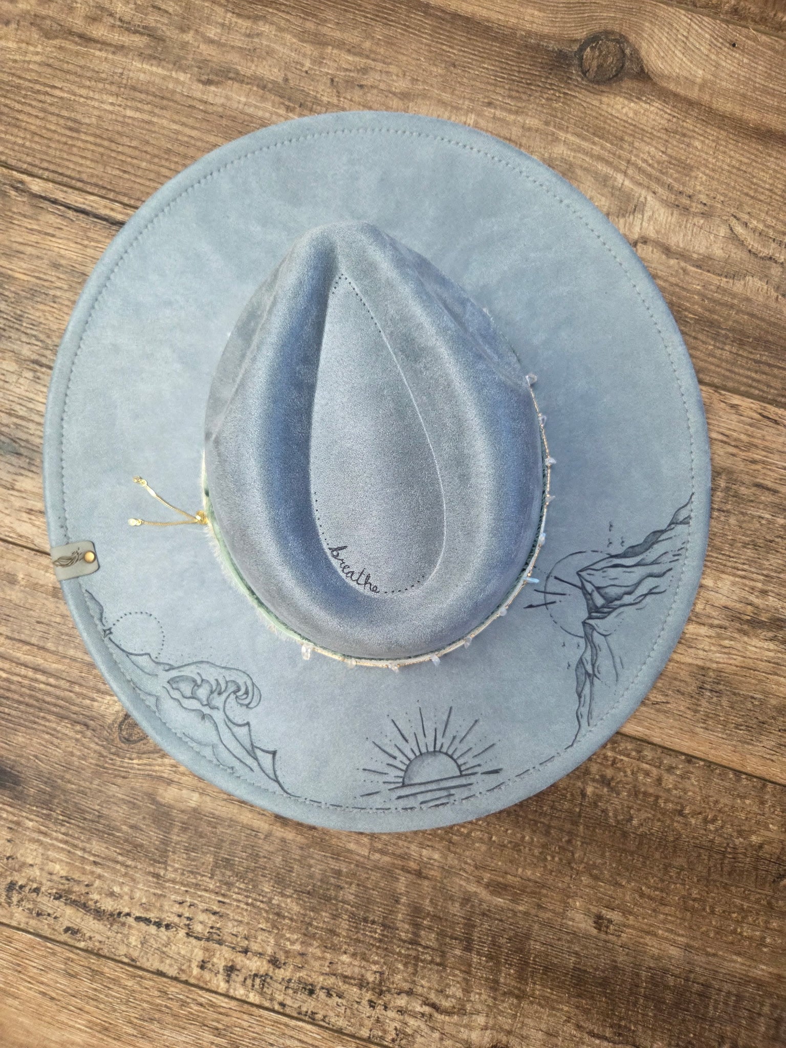 Blue cowboy hat with designs on a wooden surface