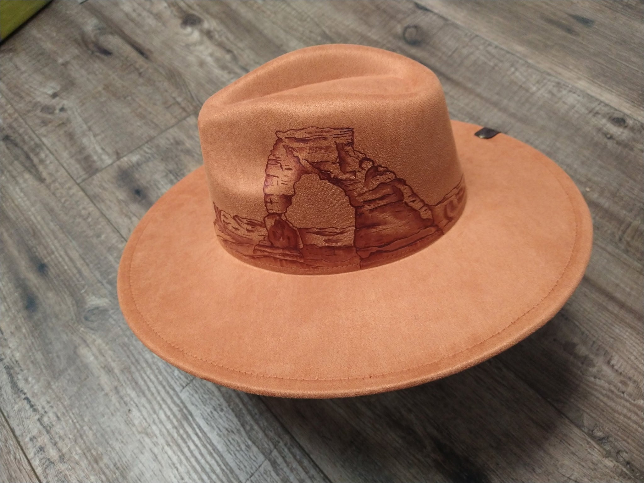 Brown leather hat with design on a wooden surface