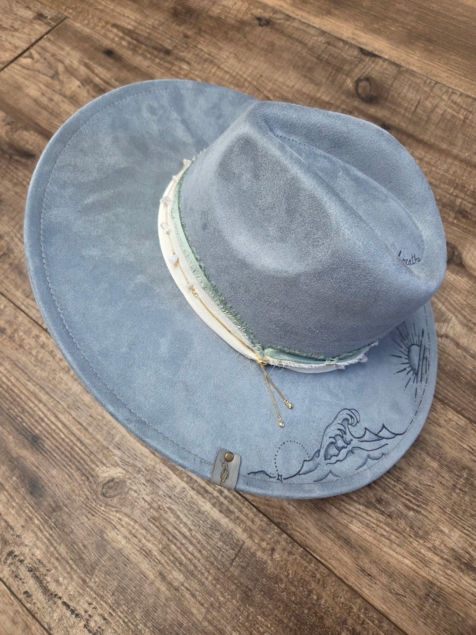 Blue suede hat with embroidery on a wooden surface
