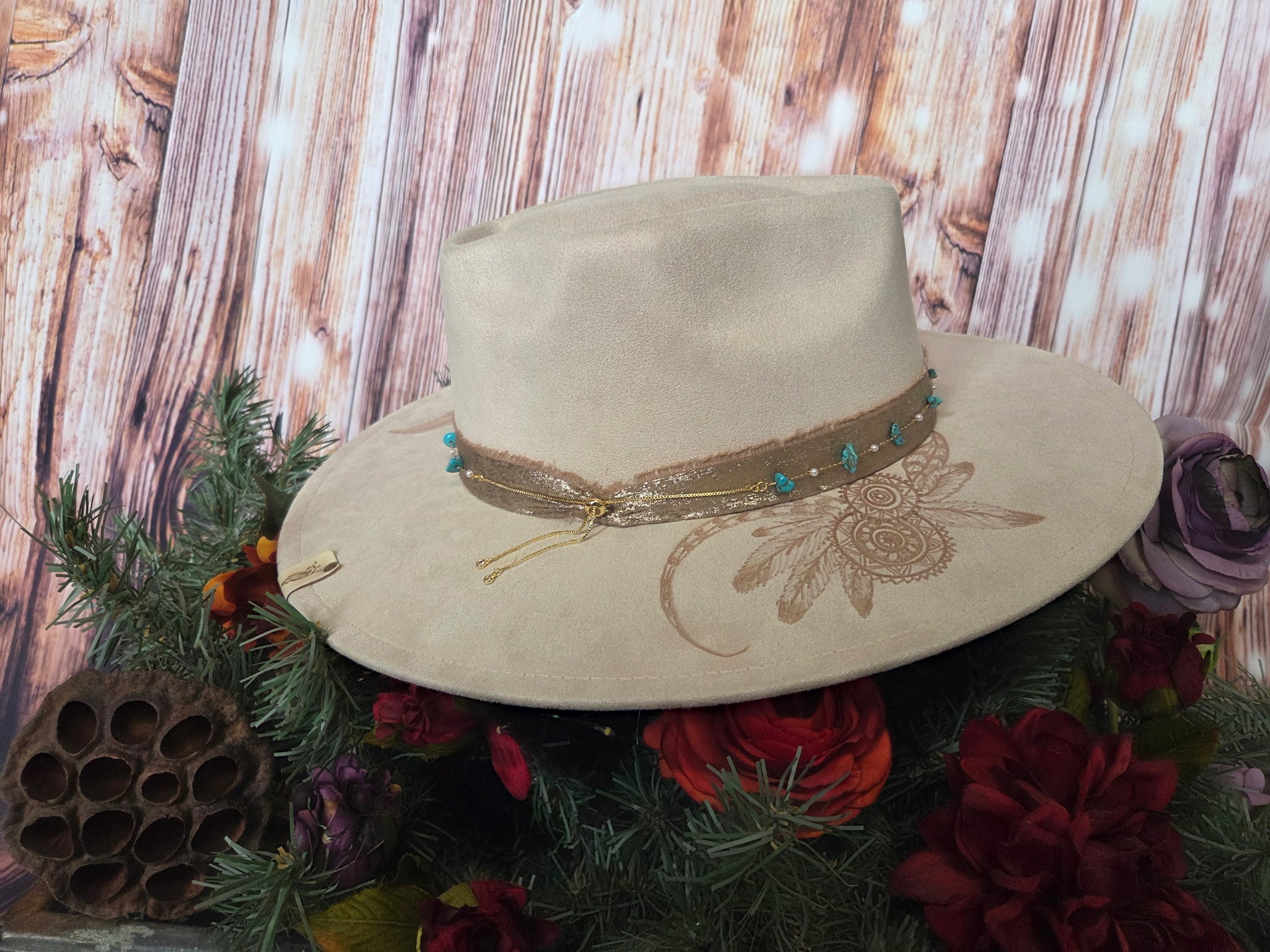 Beige hat with decorative band on a floral and wooden background