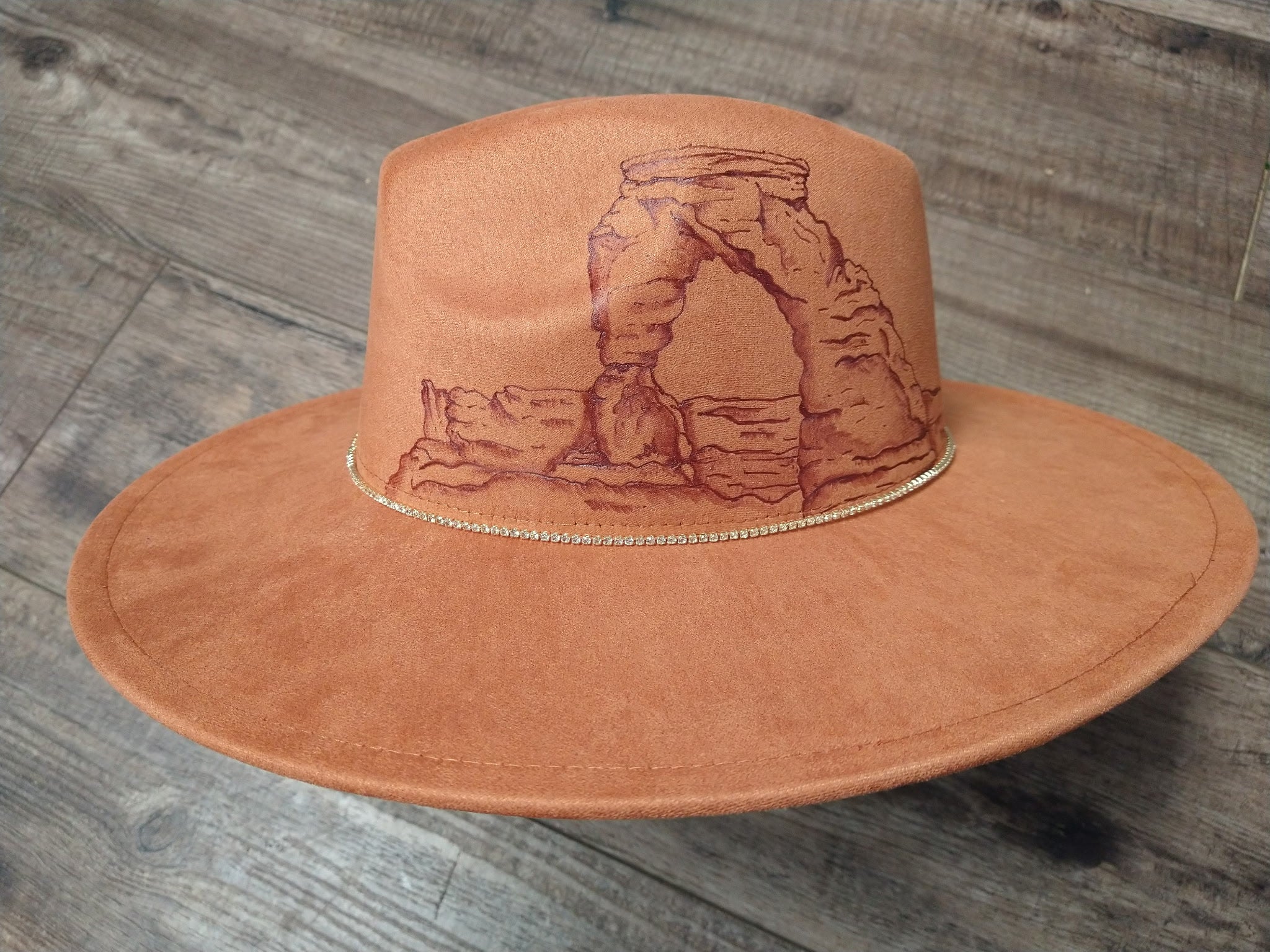 Brown hat with arch design on a wooden surface