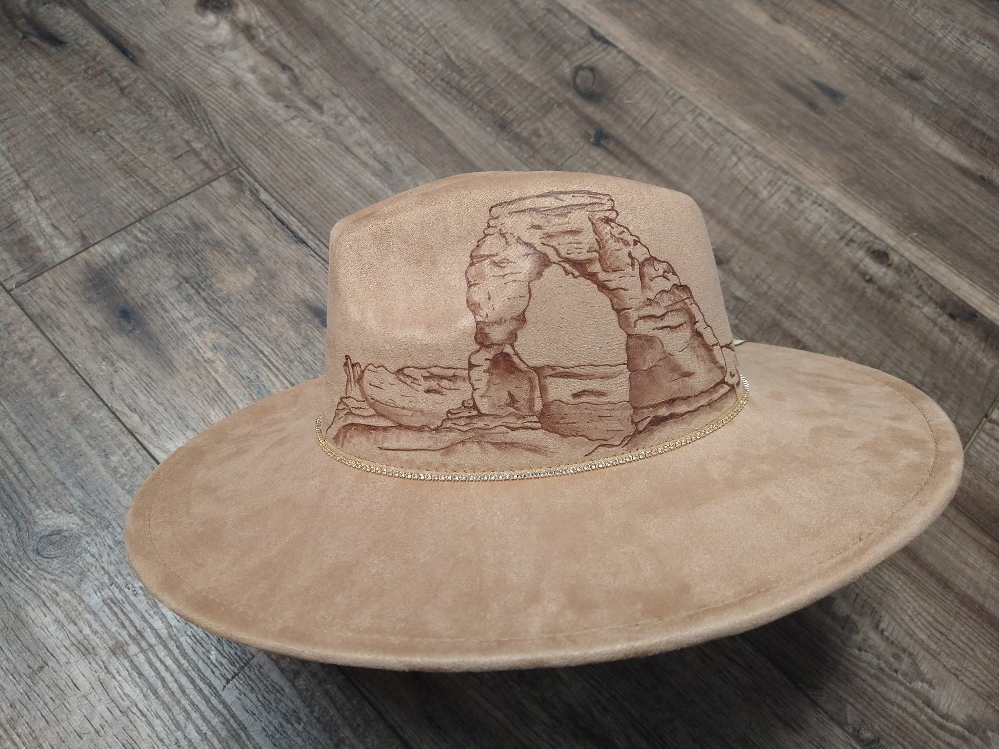 Beige hat with a desert arch design on a wooden surface