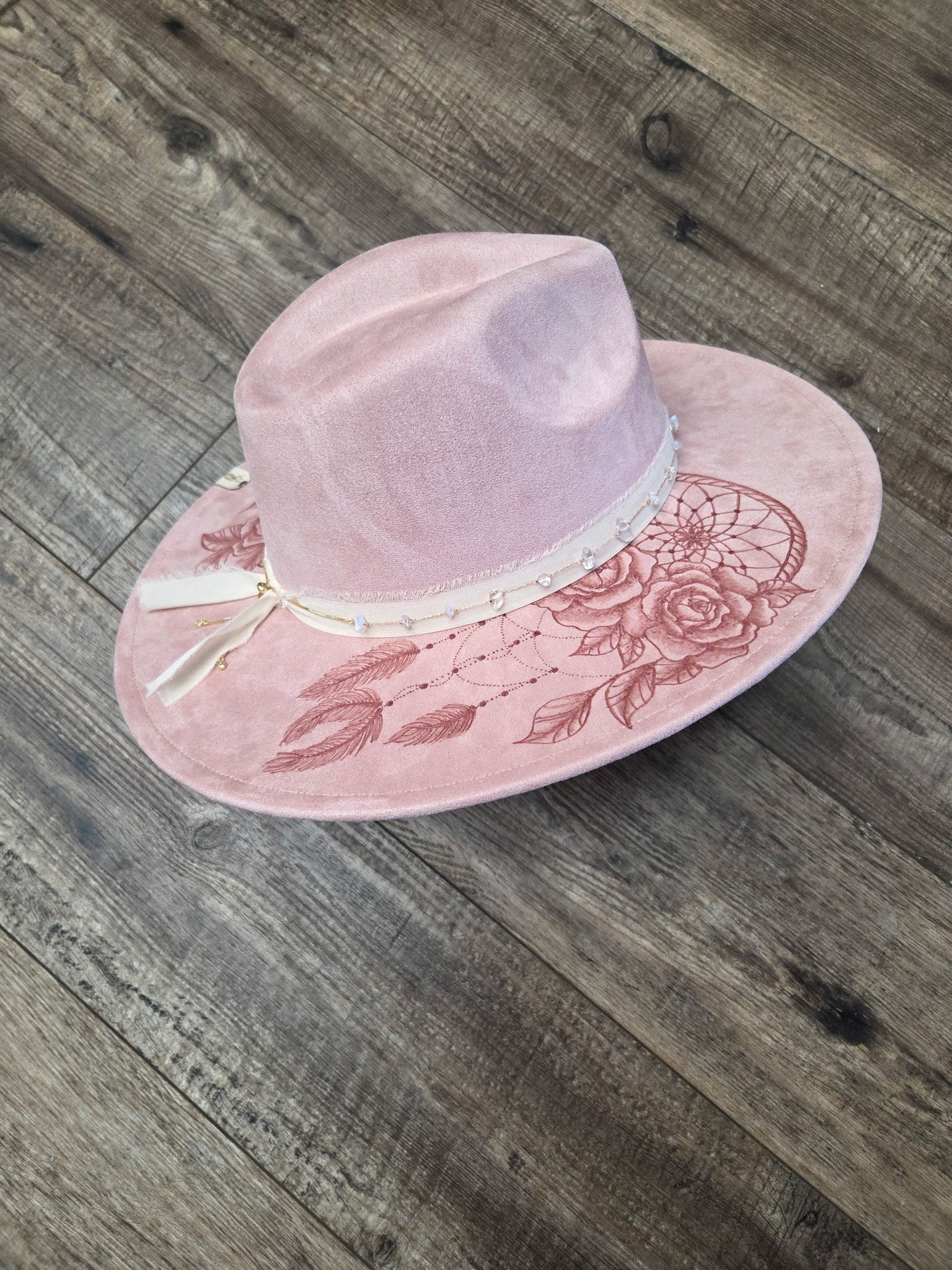 Pink hat with floral embroidery on a wooden surface