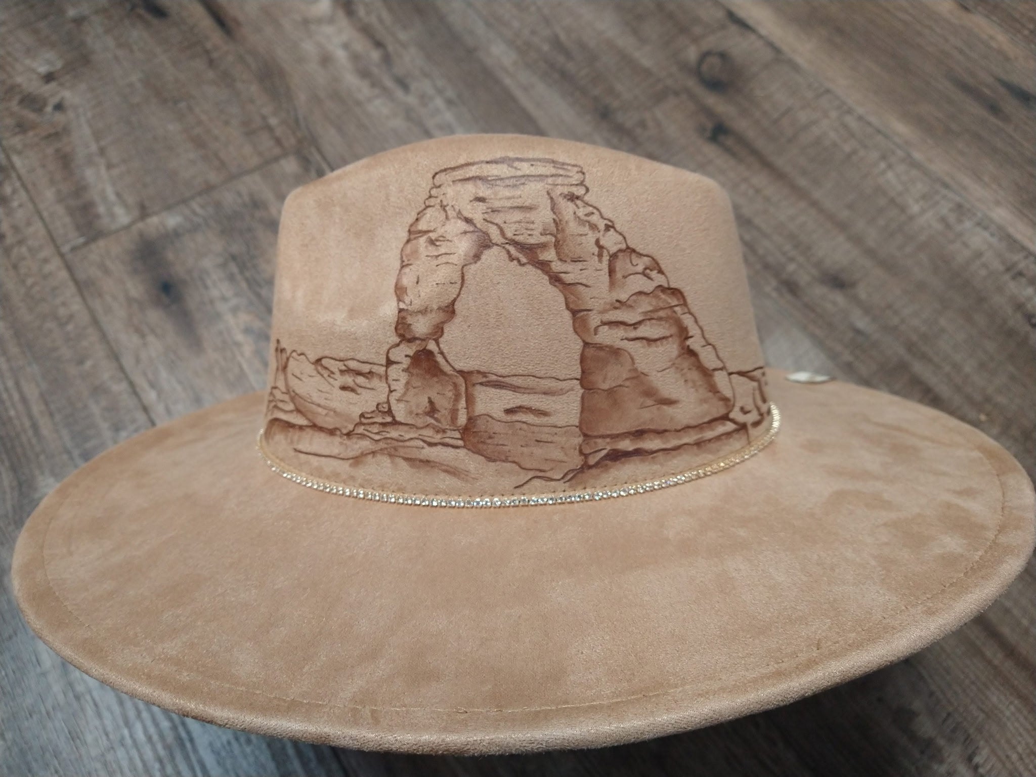 Beige hat with a desert landscape design on a wooden surface