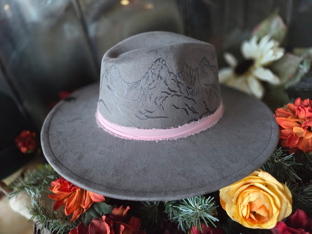 Gray fedora hat with pink band on a decorative background with flowers