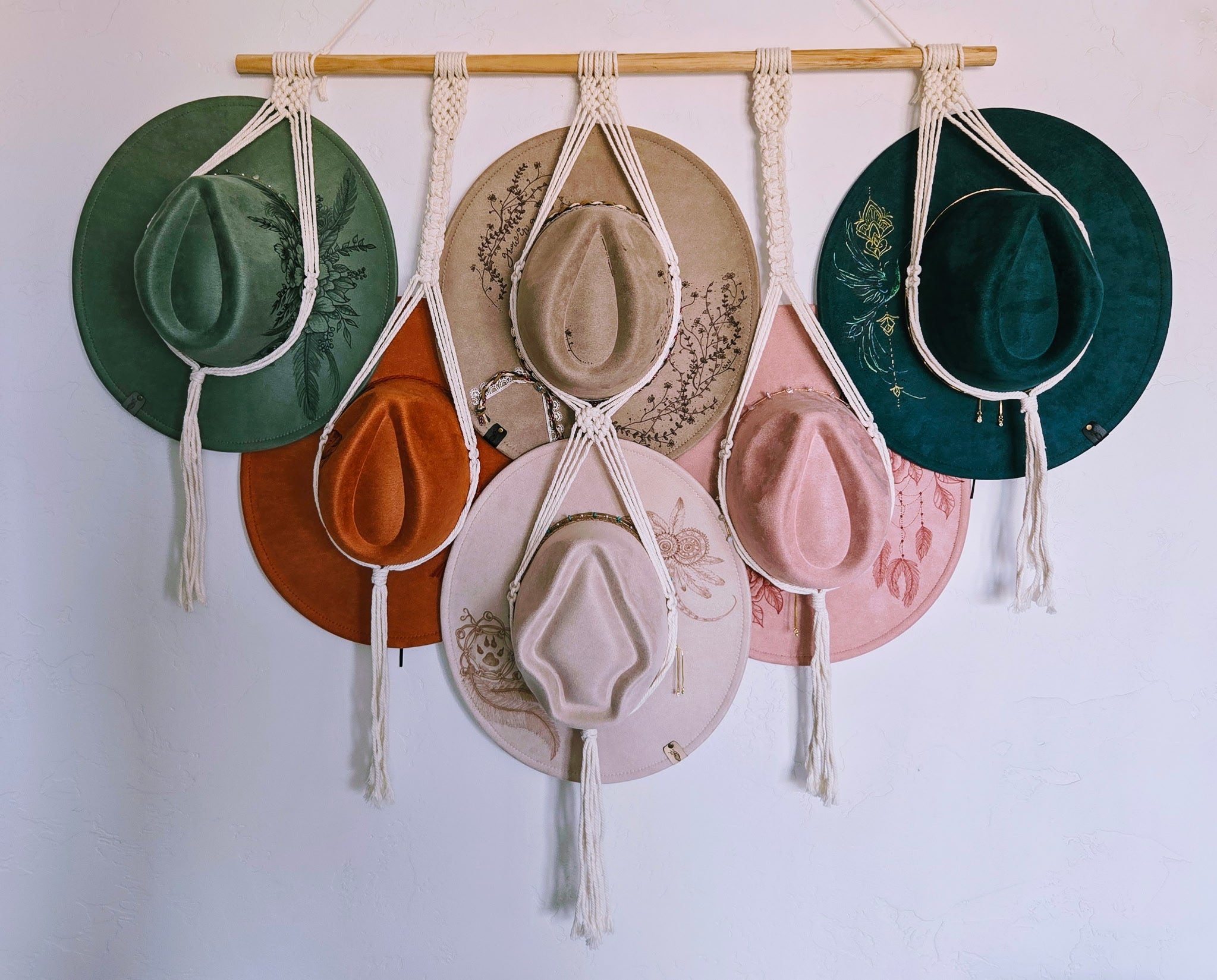Set of hats displayed on a macrame wall hanging against a white background